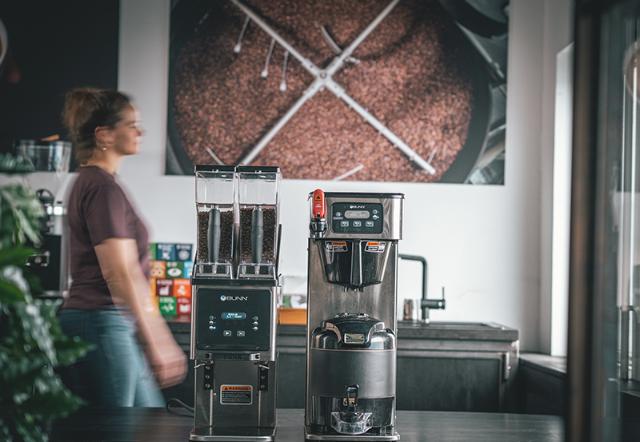 kvinde går forbi kaffebrygudstyr